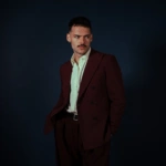 James Marriott w bordowym garniturze na ciemnym tle – zdjęcie promujące singiel Lovestruck i album Warning Signs, fot. Sam McMahon